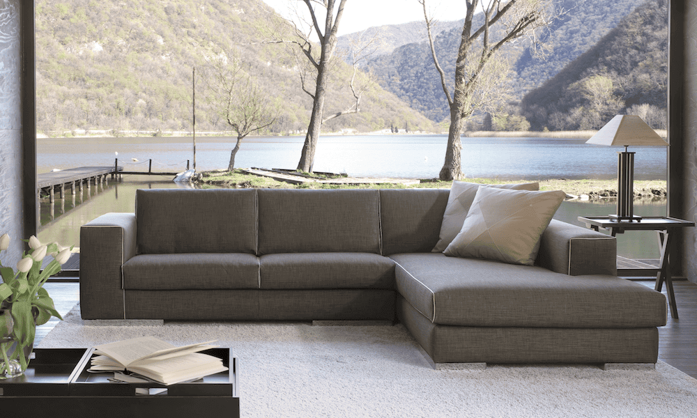 Una casa con vista sul lago e in salotto si vede Blow, il divano angolare con chaise longue realizzato su misura da Tino Mariani.