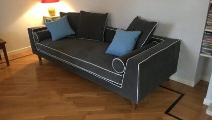 Dettaglio del divano nero Tino Mariani, cuciture bianche a contrasto e cuscini blu in tessuto Made in Italy.