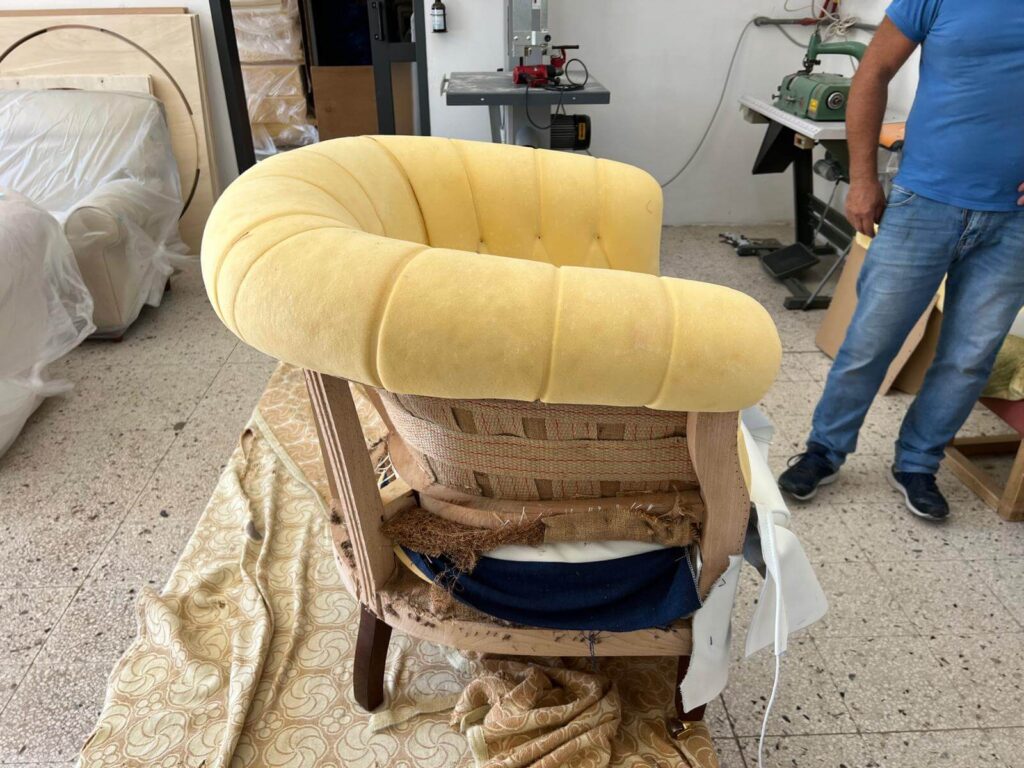 Tappezziere al lavoro su poltrona in pelle graffiata – restauro Milano